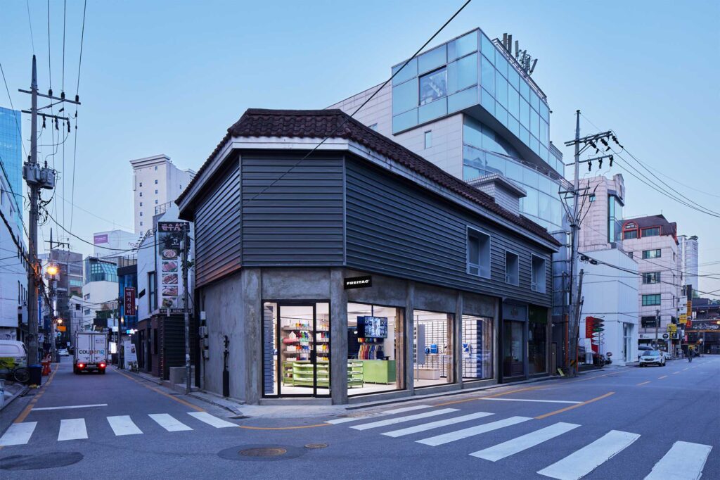 Very wide angled exterior view at dusk of Freitag Seoul Apgujeong store facade and entrance, designed by Schemata Architects.