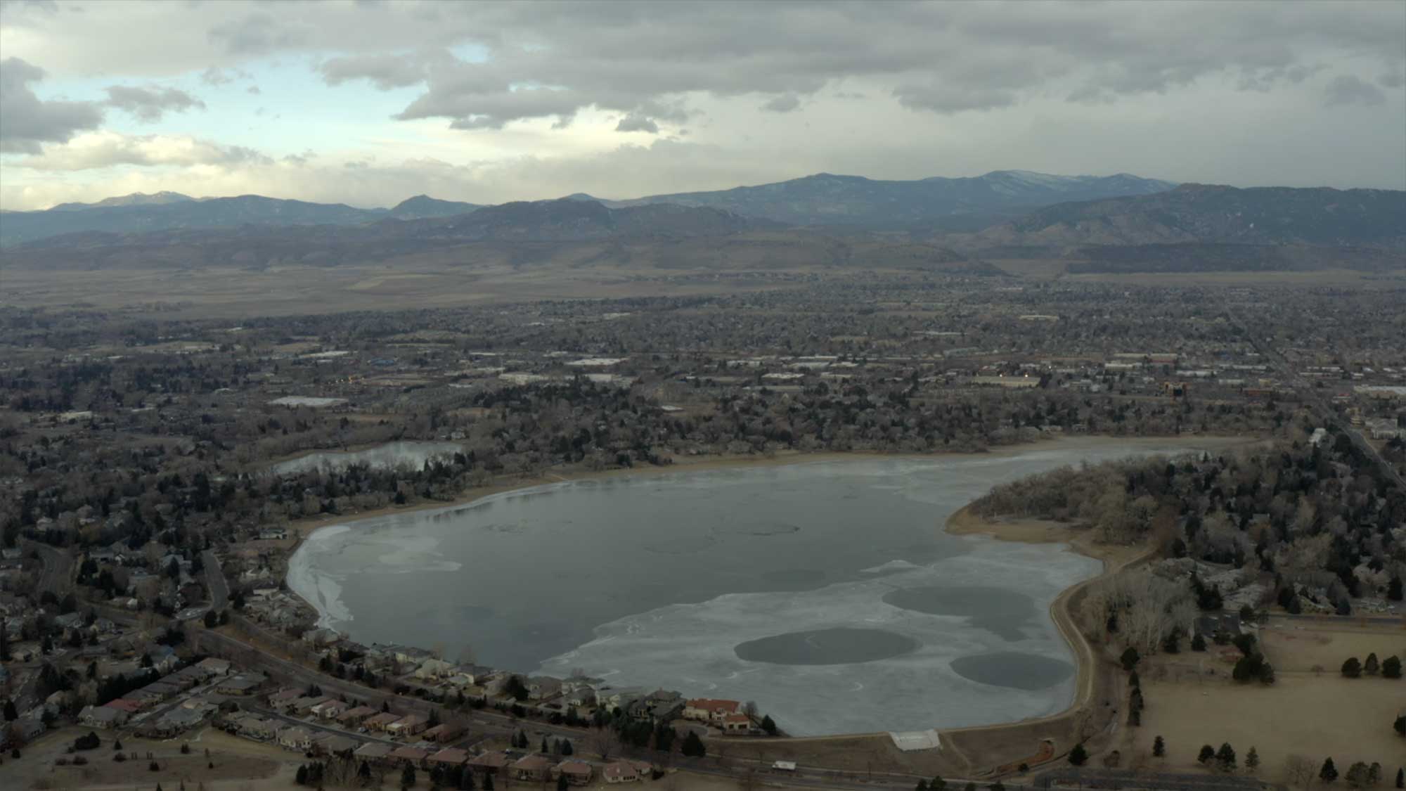 Aerial view of partially frozen lake with homes and trees in U.S.