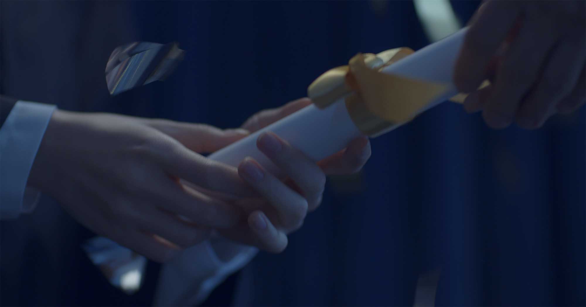 Graduate’s hands receiving diploma from dean in Samsung Life Insurance video