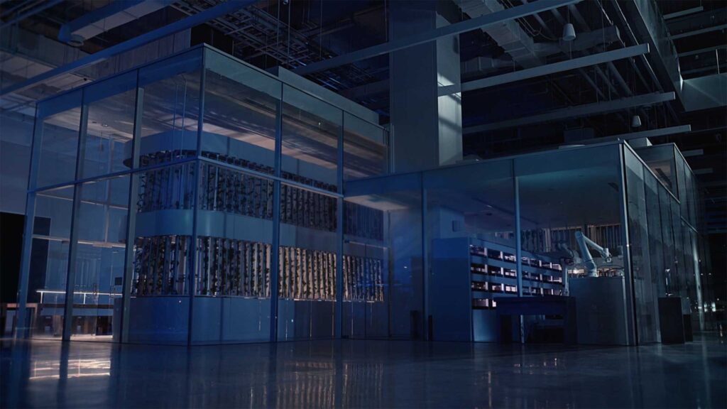Night view of Smart Farm with glass structure and robotic arm.
