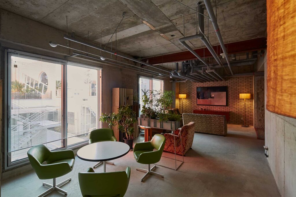 Wide shot of hotel lounge at D&Department Jeju by Arario, designed by Schemata Architects, with green chairs, sofas.