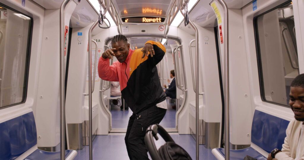 Man striking playful pose inside Milan metro train.