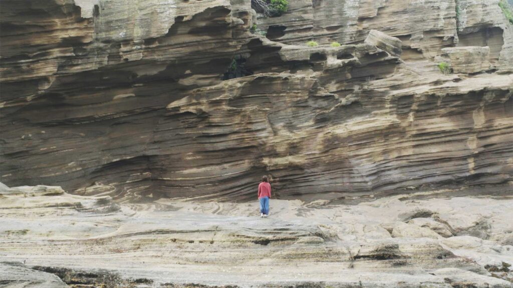 North korean female refugee stands facing massive lava rock formation on southern coast of Jeju Island South Korea in yongmori