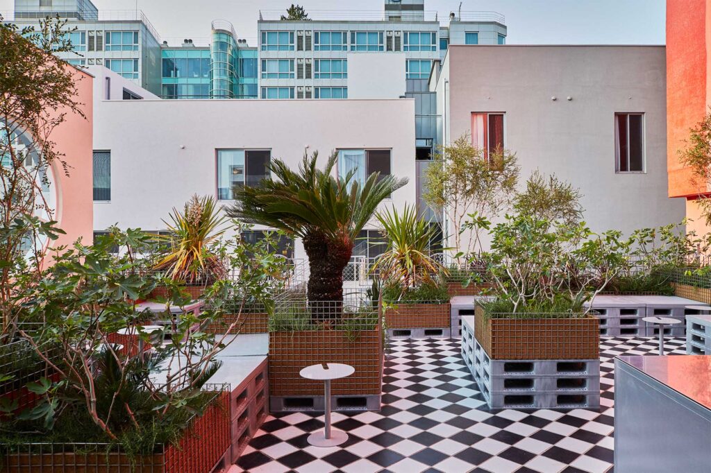 Terrace with black and white checkered pattern and plants in trays stacked on palettes at D&Department Jeju by Arario.