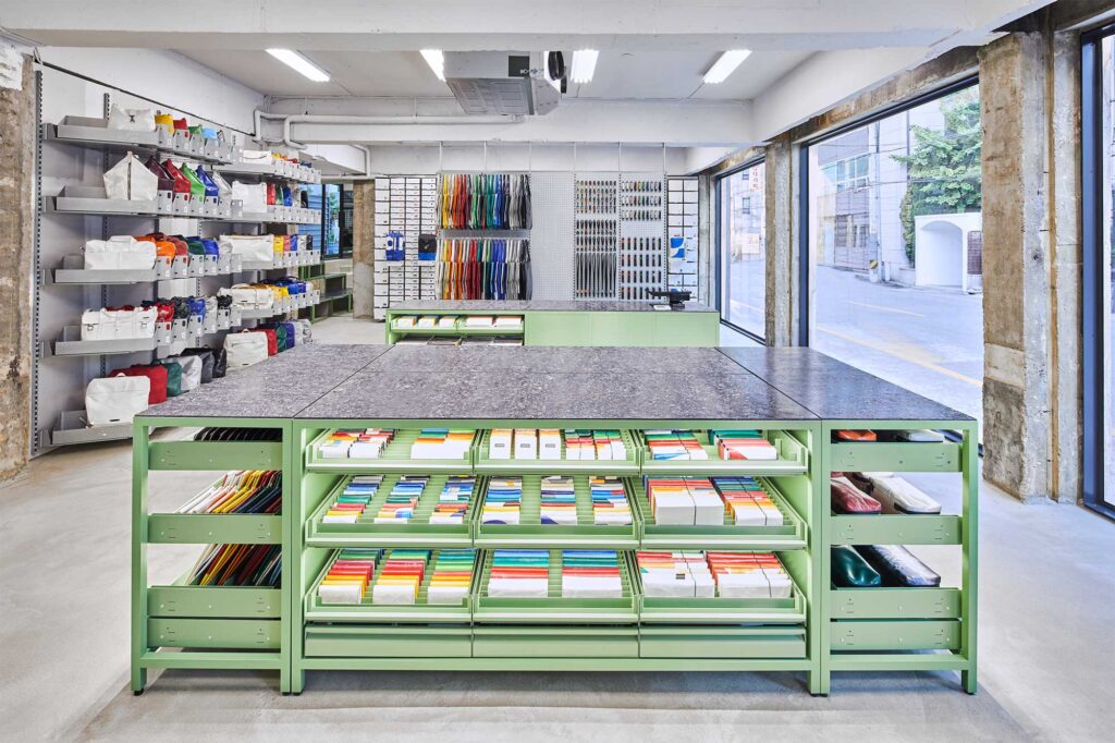 Wide interior view of Freitag Seoul Apgujeong store with stylish mint green counter in foreground displaying accessories.
