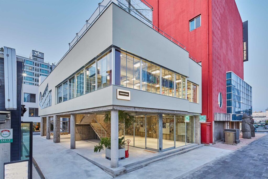 Exterior of first Freitag store on Jejudo with newest bag line above bicycle store on concrete pillars