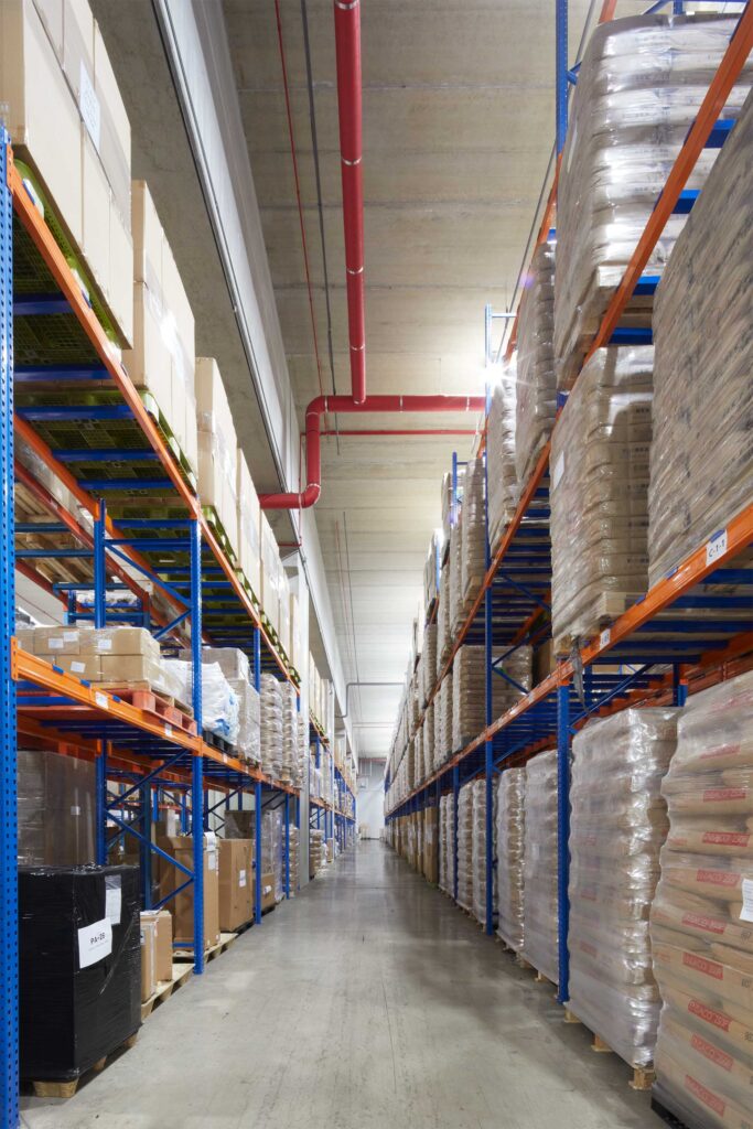 Long aisle with shelves stacked with goods in warehouse