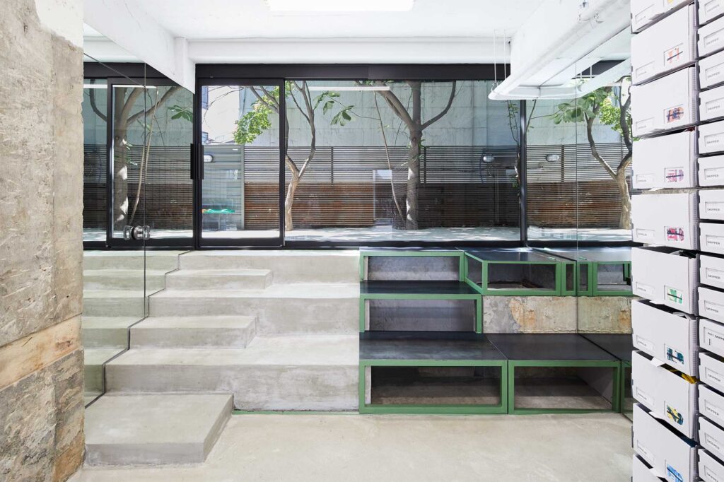 View of back end of Freitag Seoul Apgujeong store with small staircase leading up to terrace with trees.