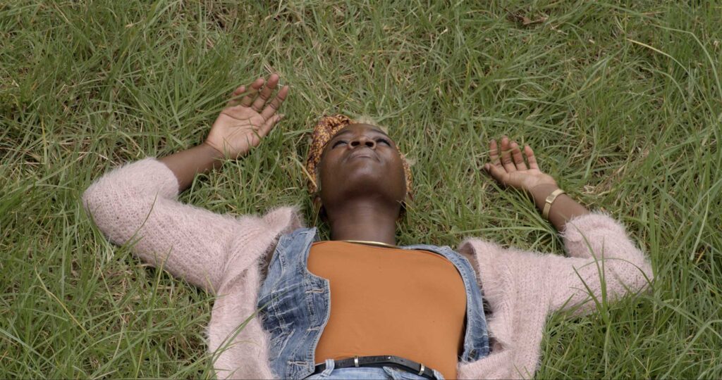 Woman with eyes closed lying in grass in Nairobi.