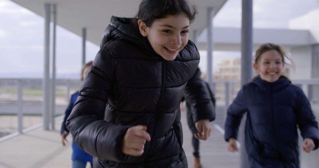 Children running through outdoor corridor at Vienna school campus.