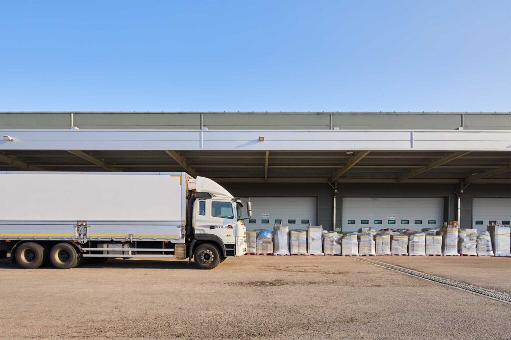 Delivery truck with stacked pallets under clear sky.