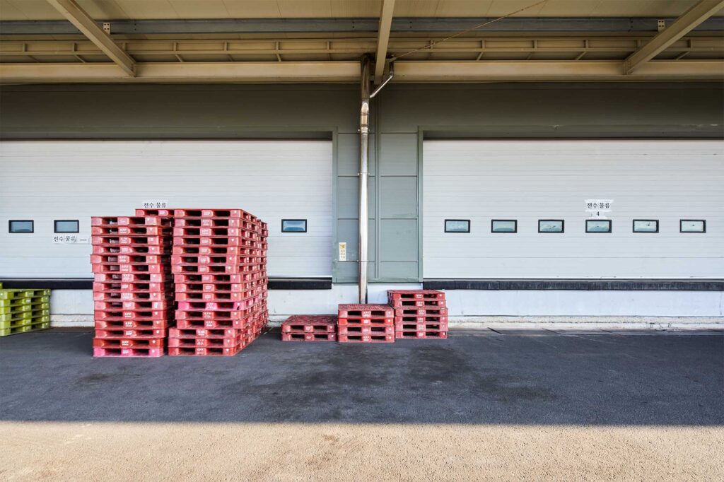 Stacked red pallets at logistics dock outside Seoul.