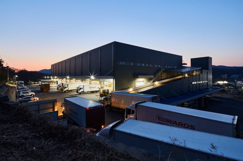 Trucks at loading bays of logistics center at dusk.