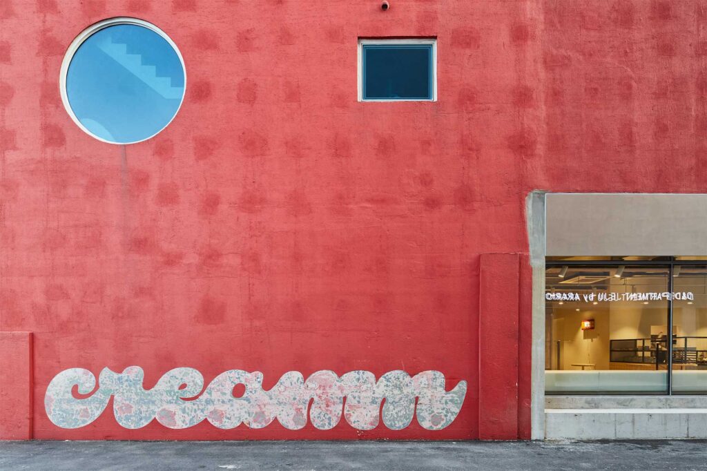 Facade of cafe Cream in red with stylish logo and glass opening showing interior