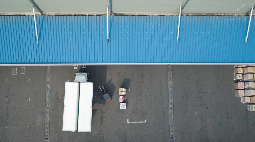 Drone view of truck unloading at logistics dock.