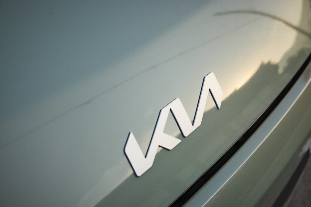 Kia EV3 rear badge detail reflecting landscape and soft light.
