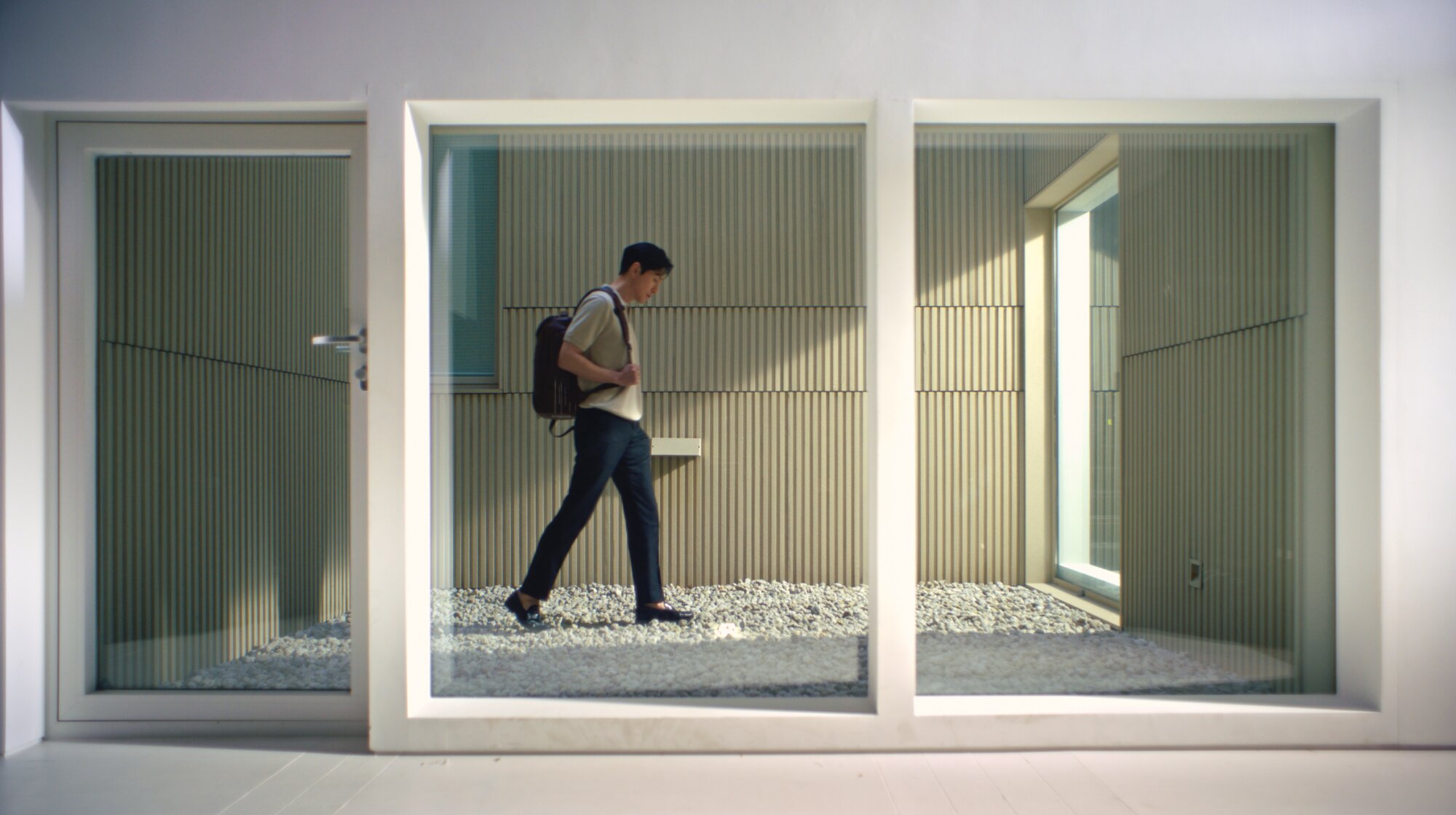 Jung Sung Il walking through architectural courtyard wearing Piquadro Seoul