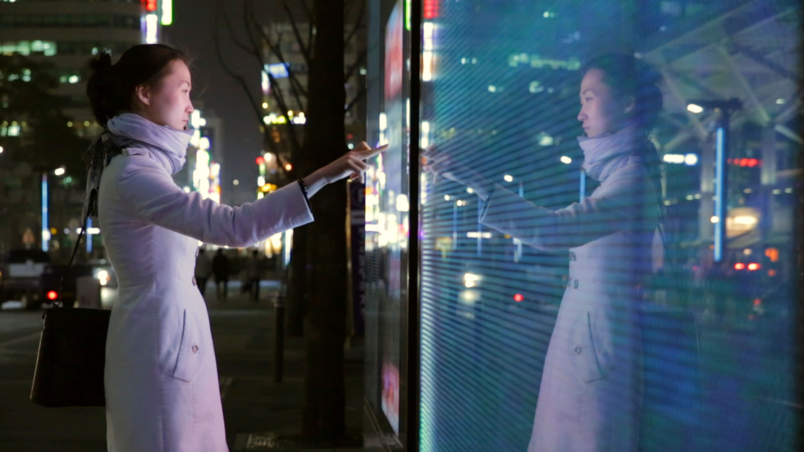Young Korean journalist interacting with digital screen at night in Seoul for documentary ZDF Wirtschaftswunder Korea