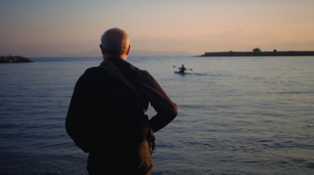 Lefteris Arapakis’s father watching him launch recycled-plastic kayak at sunset in Greece.