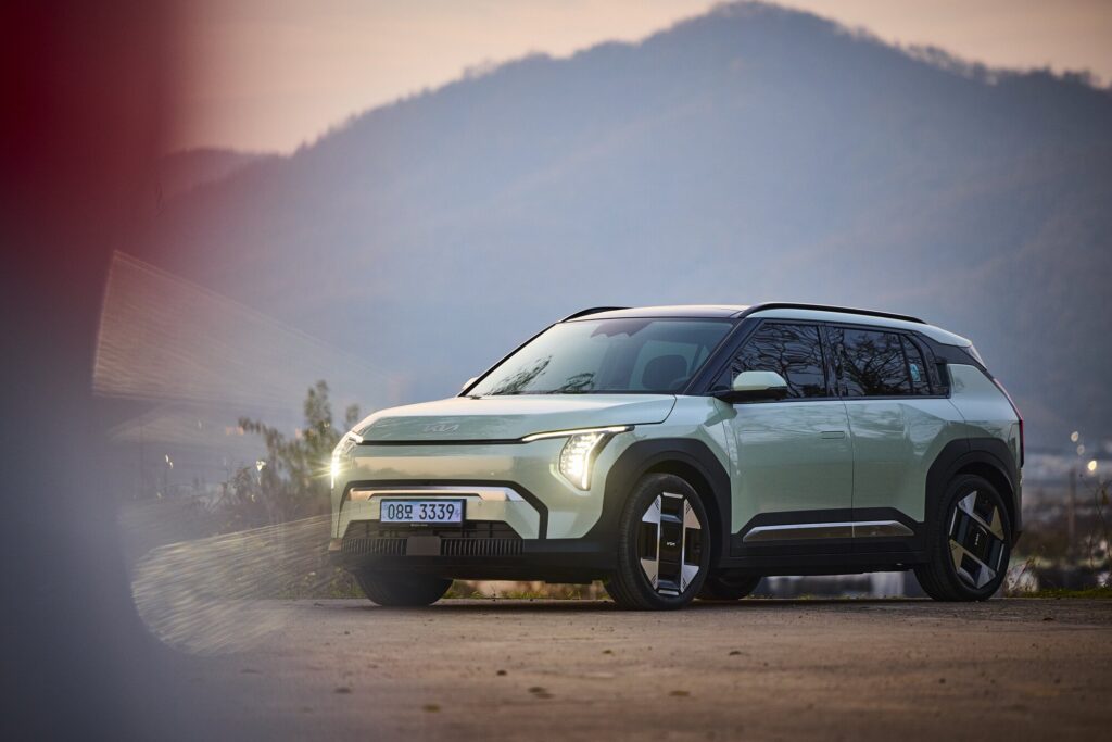 Kia EV3 at dusk on open road framed by mountains and fading light.
