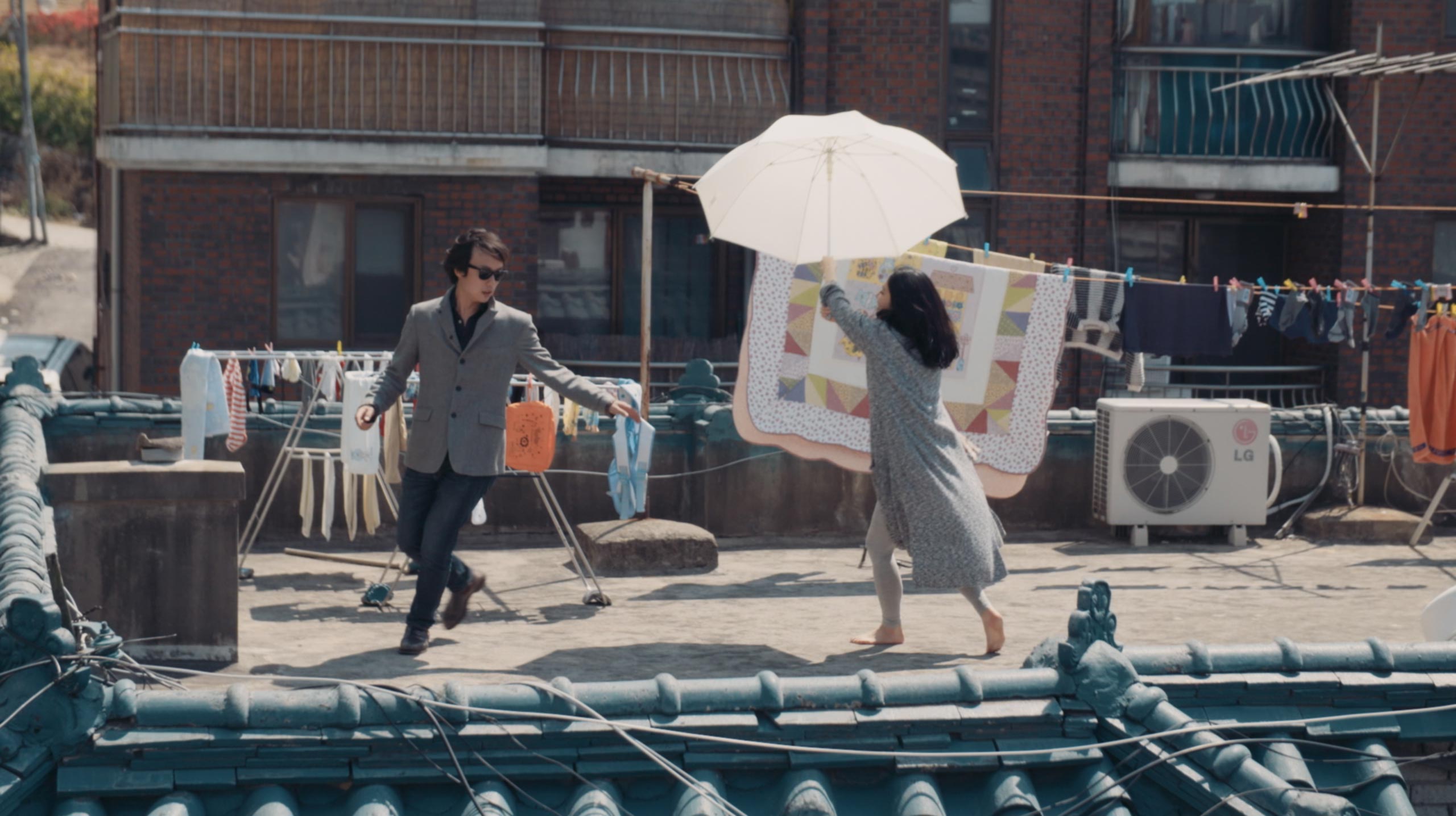 Dramaturgist Gyungsung Lee interacting on rooftop space in Seoul during Goethe Institut Seoul promo film showing everyday movement urban setting and human exchange
