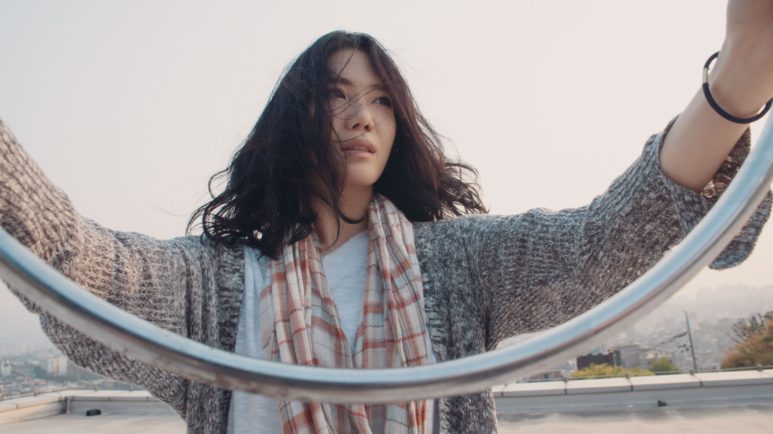 Korean actress holding metal hoop on rooftop in Seoul during Goethe Institut Seoul promo film expressing movement balance and physical gesture in urban space