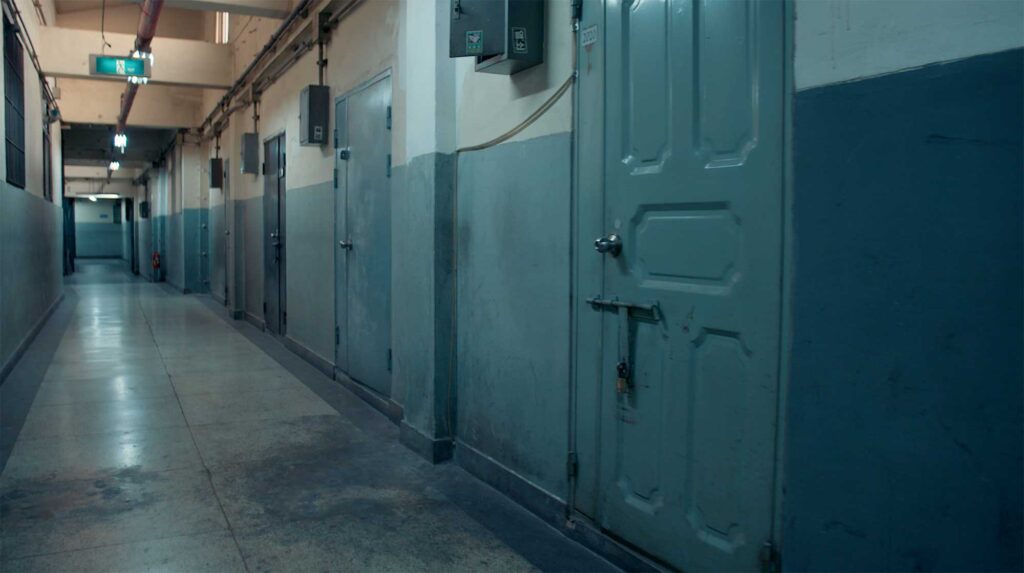 Long industrial hallway with metal doors and exposed wiring reflecting shared worker dormitories during South Korea industrial expansion era
