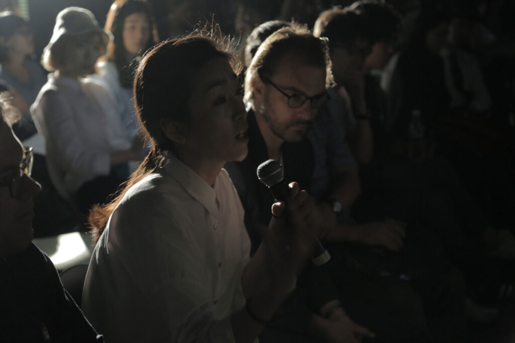 Audience member speaking into microphone during 7th Encounter at Art Center Nabi taking part in open exchange about city life and urban observation in Seoul
