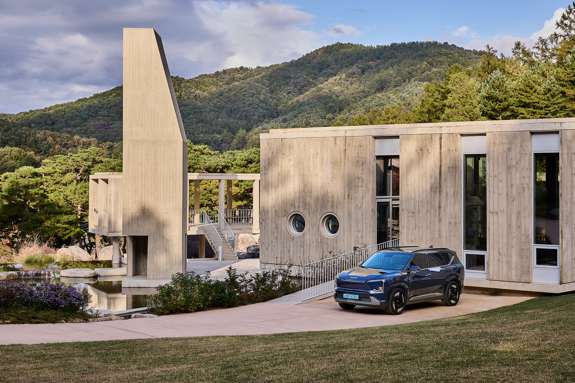 Kia EV5 framed by Médongaule concrete architecture and mountain landscape