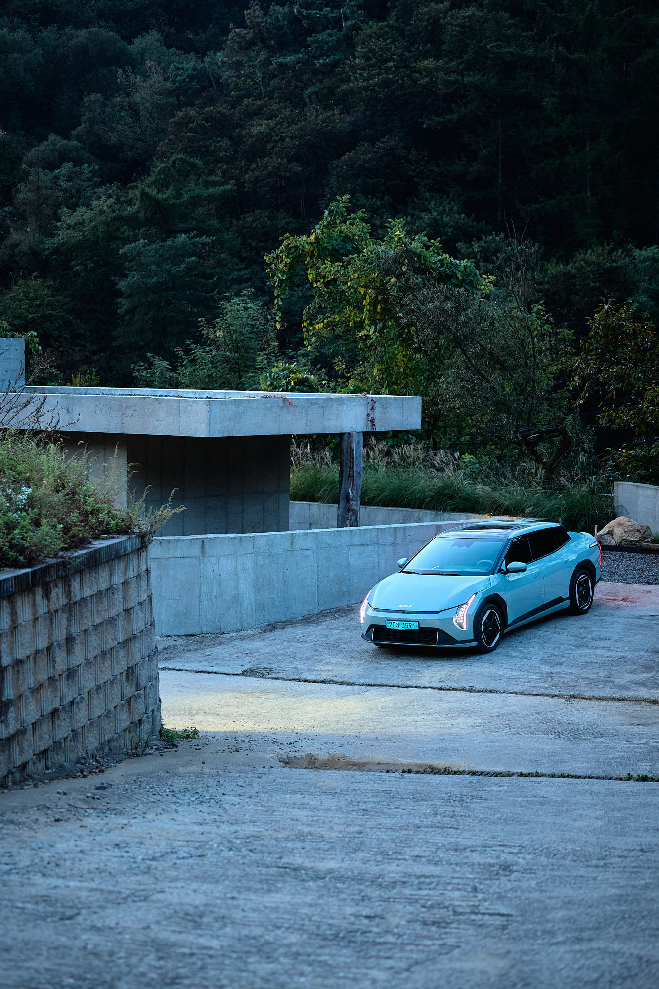 Kia EV4 framed by Myök concrete architecture and dense forest