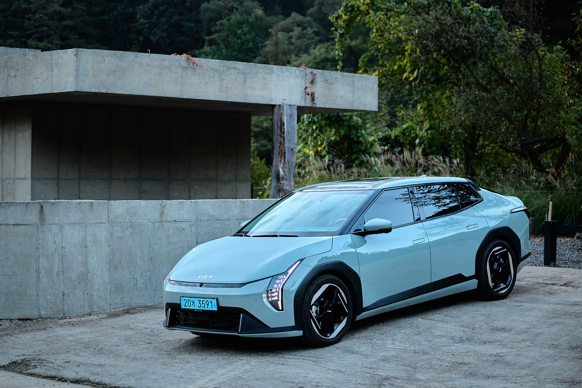 Kia EV4 framed by Myök concrete architecture and forest landscape
