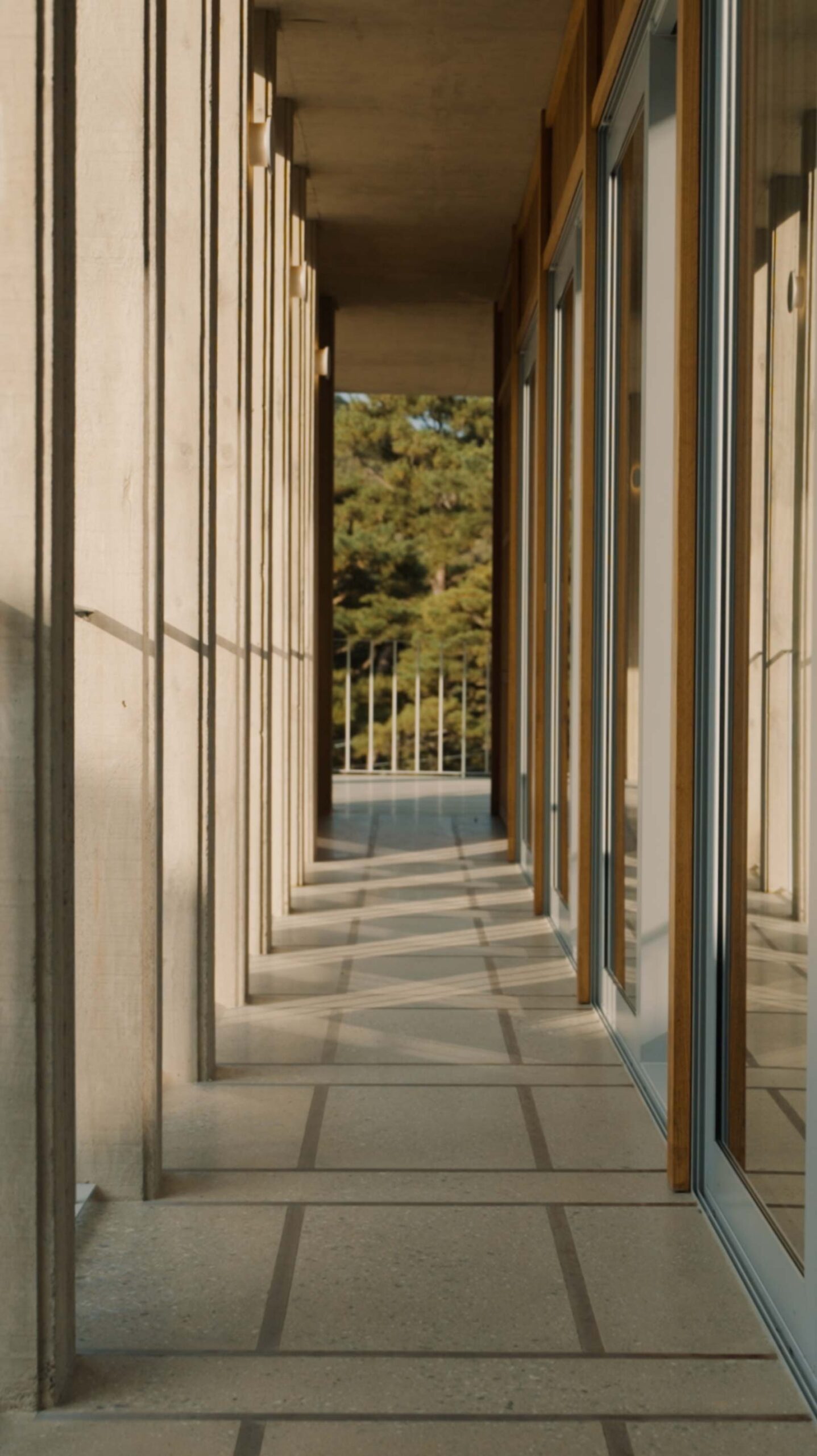 Sunlit concrete corridor and glass facade at Médongaule in Yangpyeong