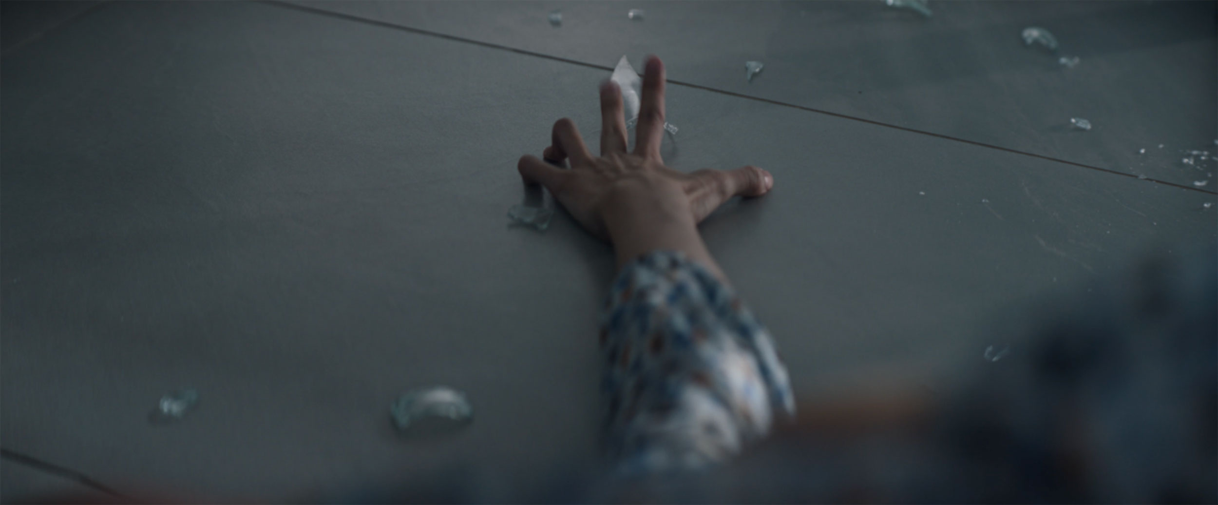 Hand reaching across broken glass during home invasion in IDOLS