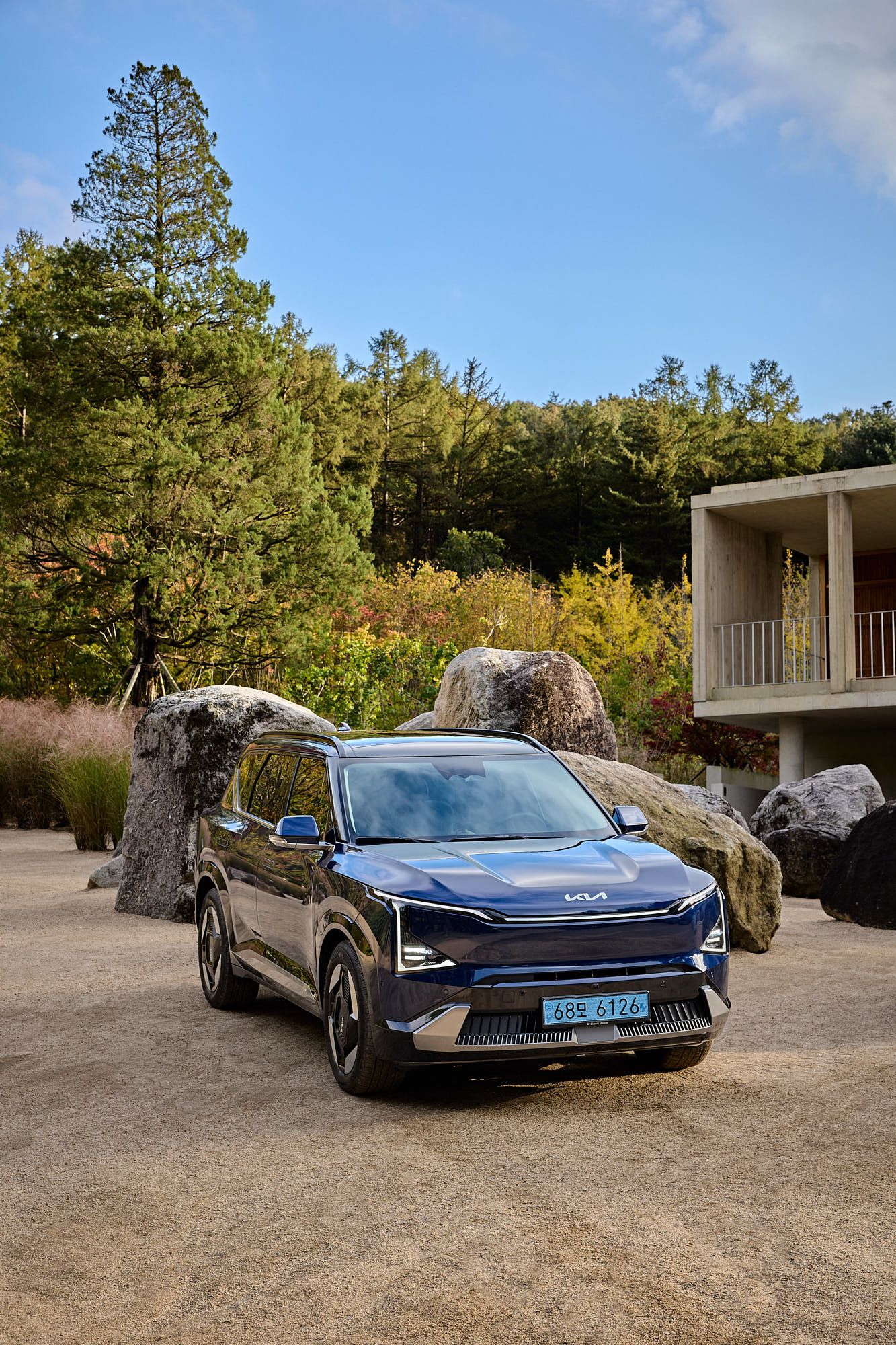 Kia EV5 framed by stone garden and Médongaule concrete architecture