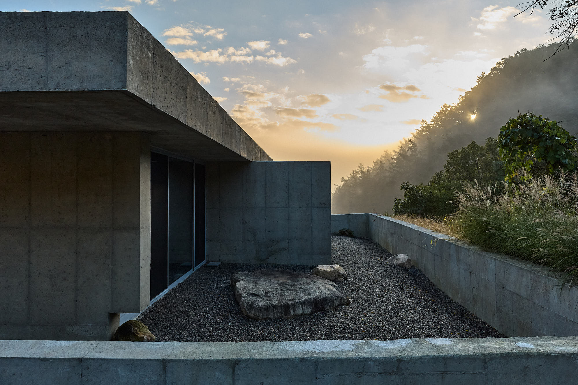 Myök concrete architecture and stone courtyard at sunrise