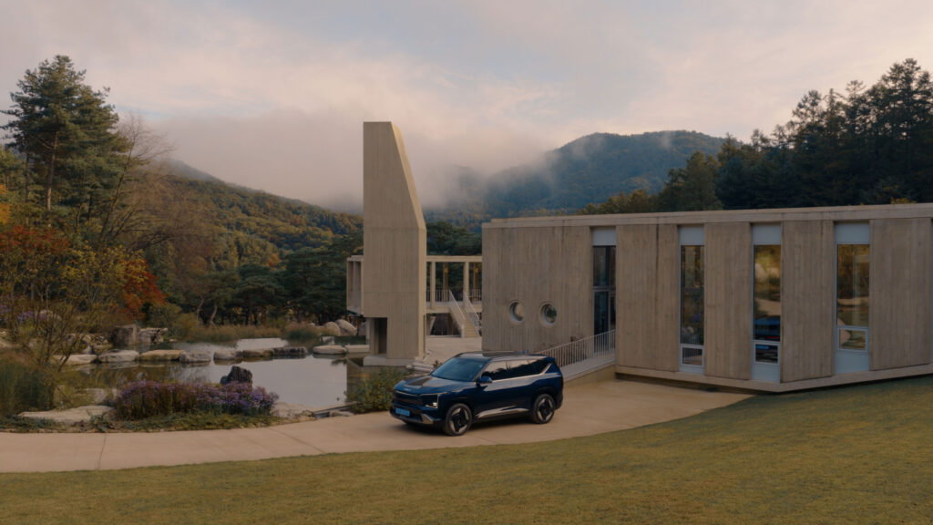 Poster Image of Kia EV5 framed by Médongaule concrete architecture and misty mountains
