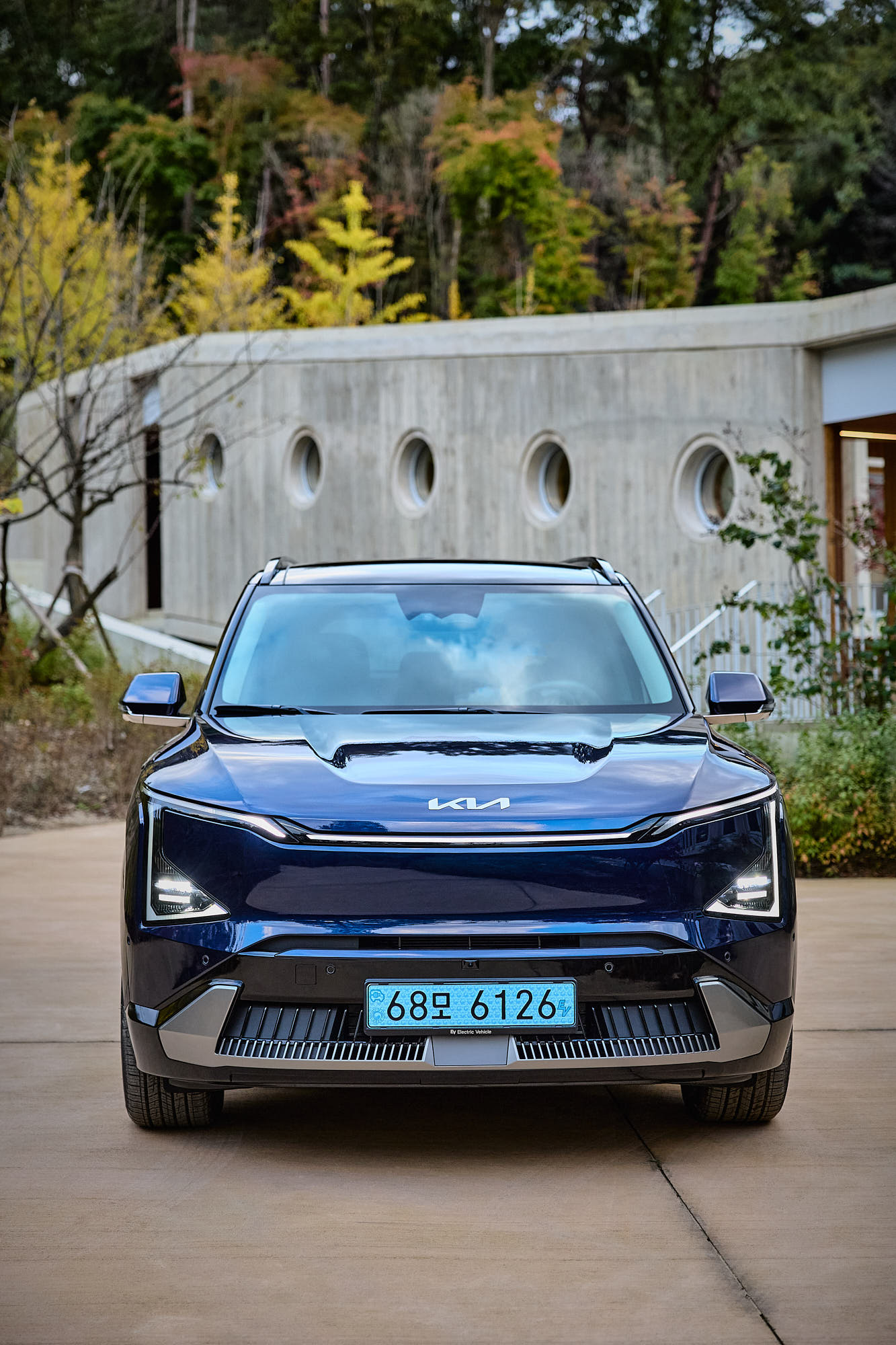 Front view of Kia EV5 against Médongaule architecture and autumn landscape
