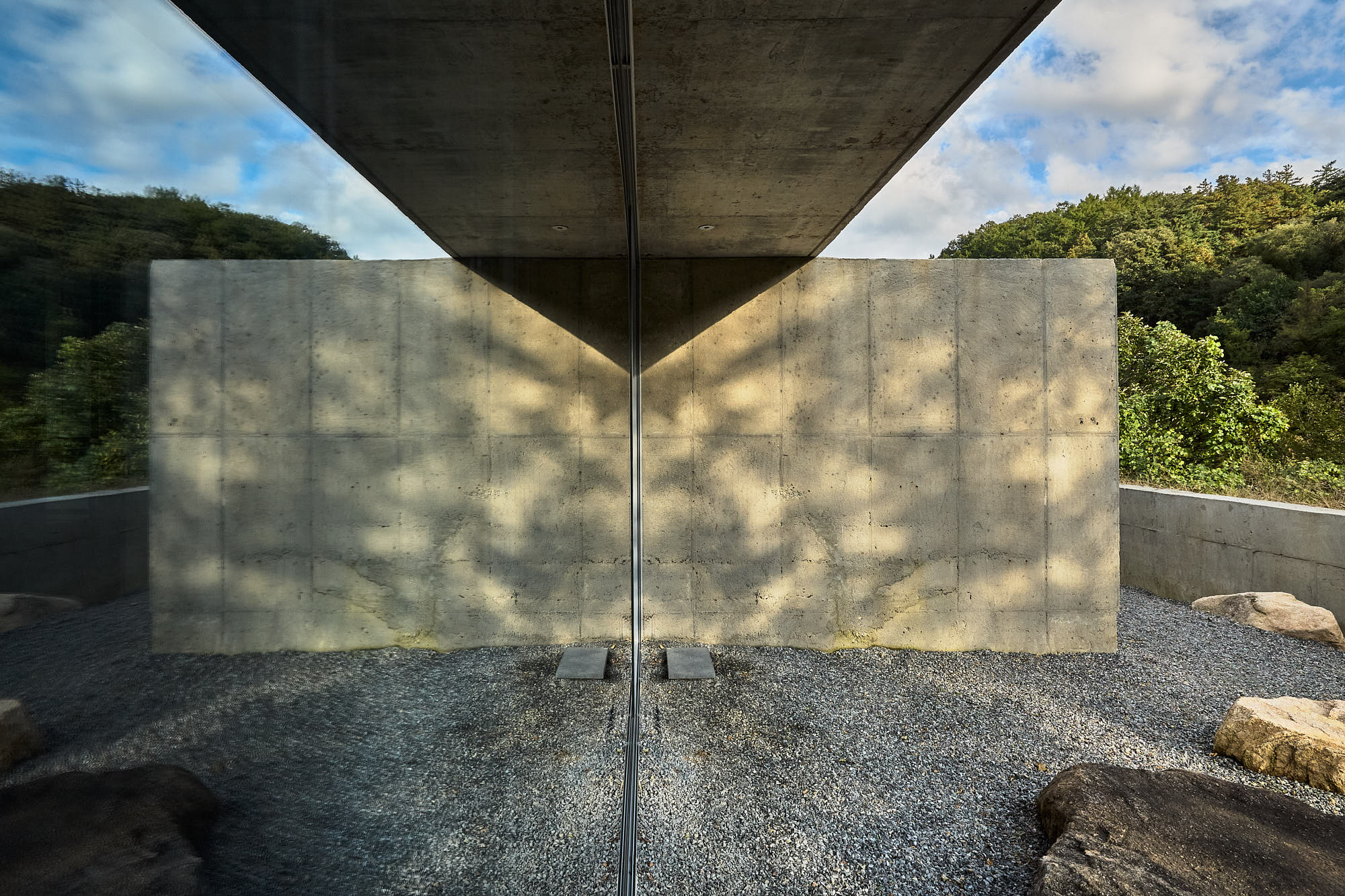 Concrete wall and forest reflected in glass at Myök bathhouse