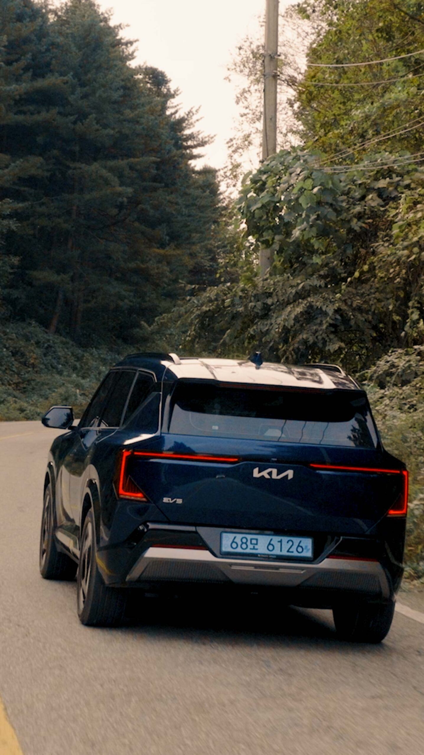 Rear view of Kia EV5 driving along a forest road near Médongaule