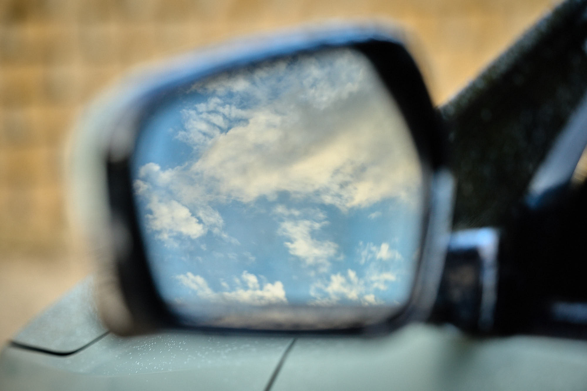 Kia EV4 side mirror reflecting blue sky and clouds